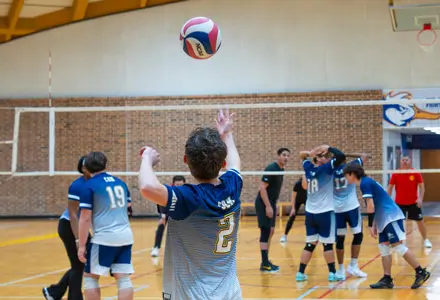 Student serving at a volleyball game in the gym.