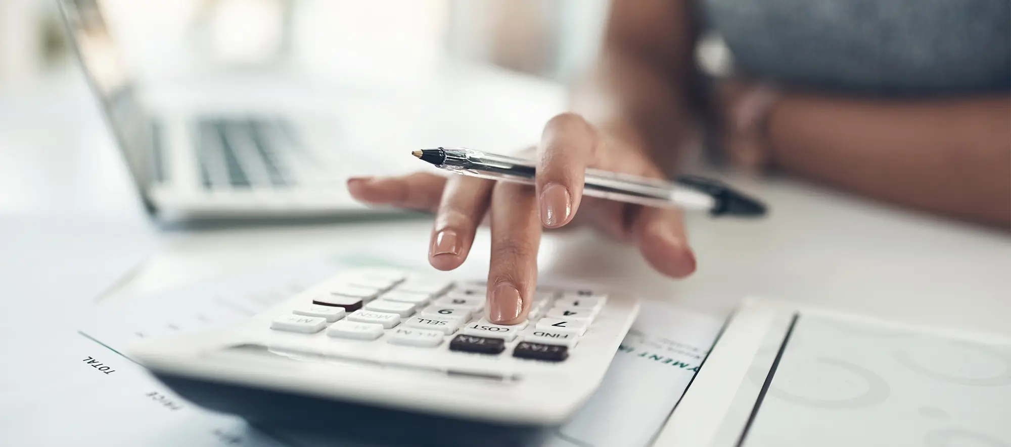 Close up of hand using calculator at desk.