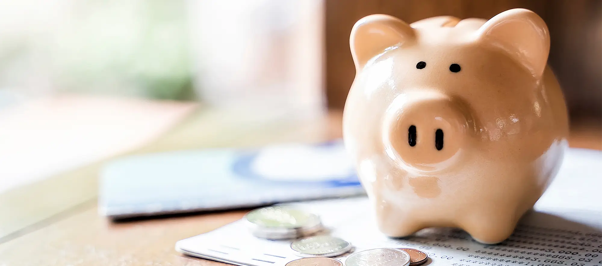 Piggy back sitting on a table with a few coins.