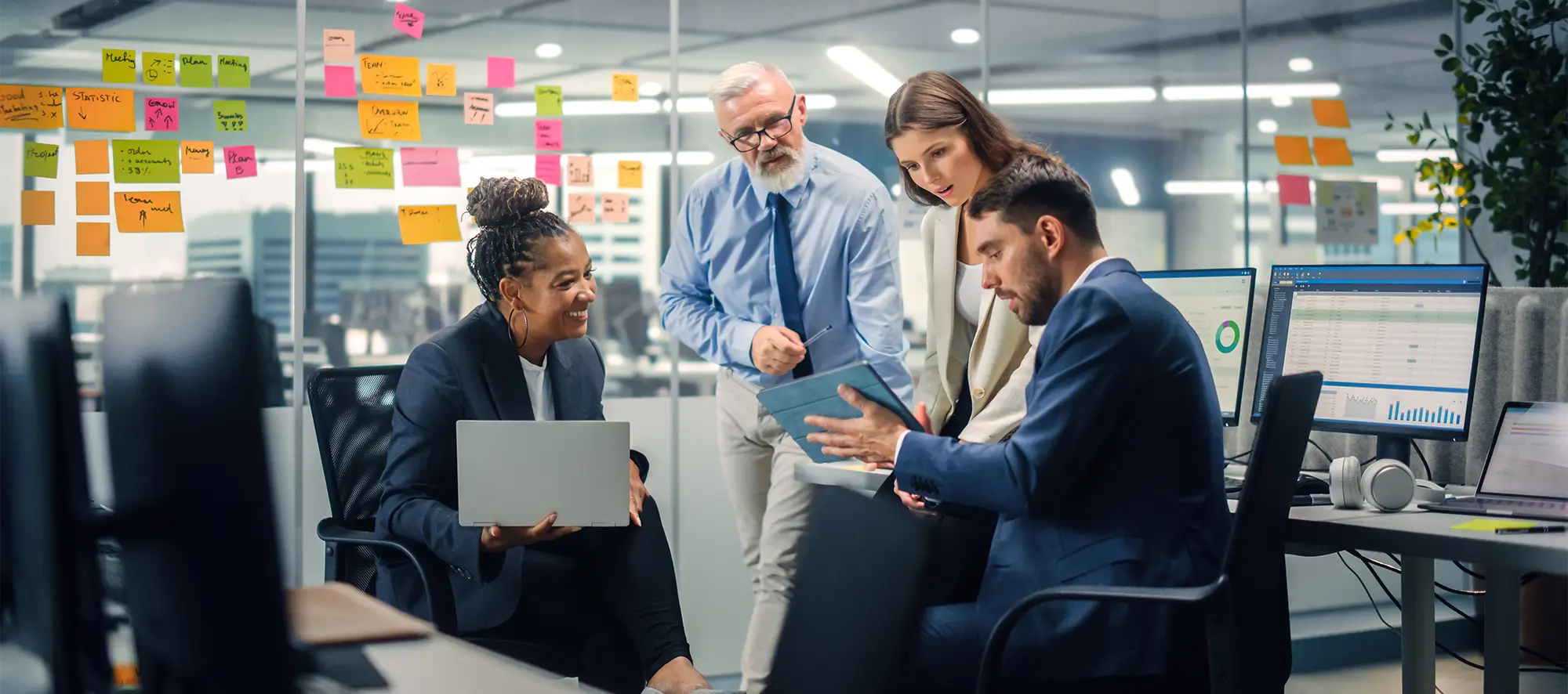 Business people in an office looking at laptop and clipboard.