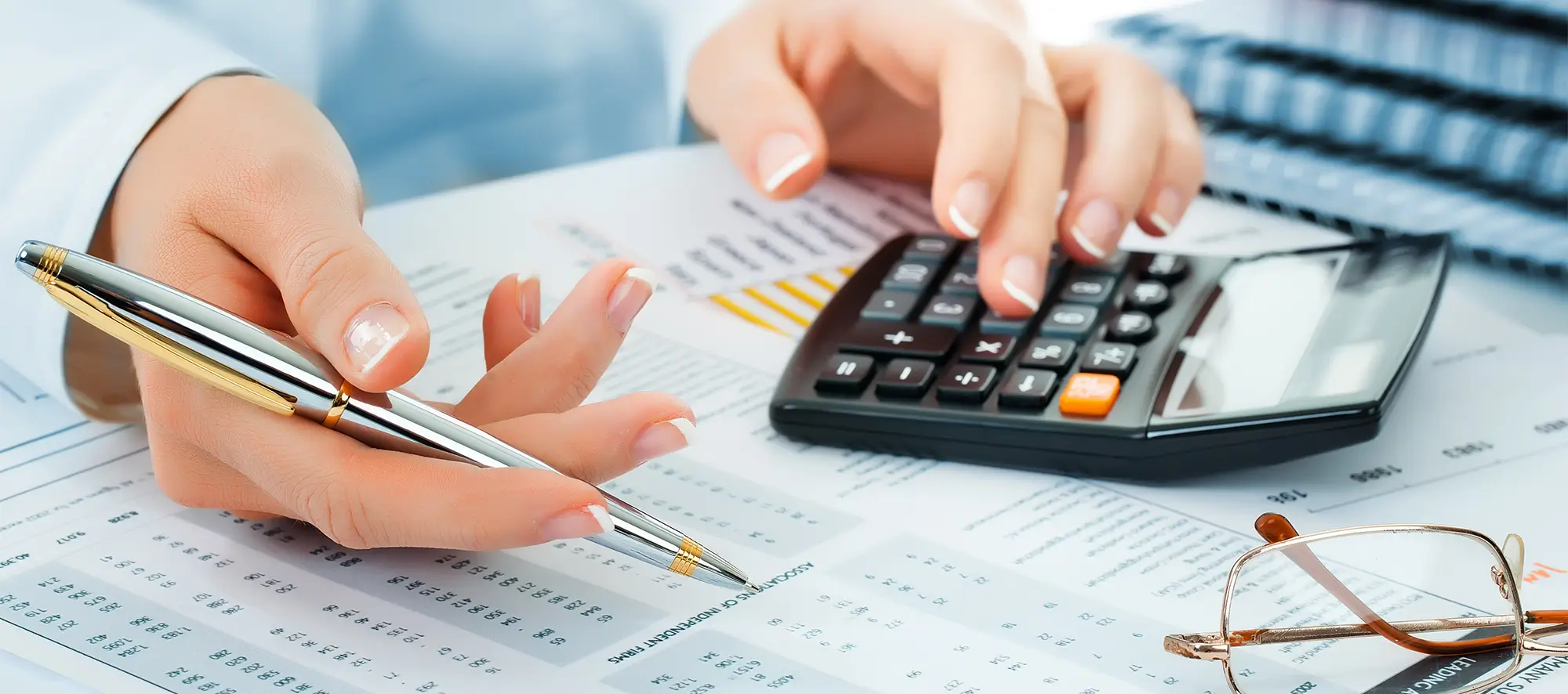 Person sitting at desk crunching numbers with a calculator. 