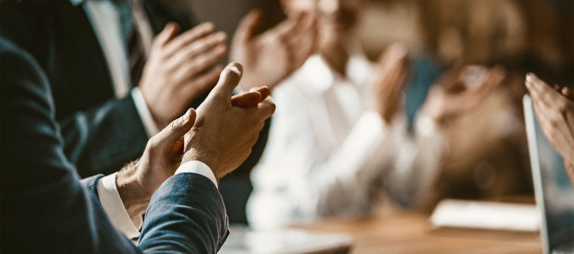 Board of people clapping while at a conference table.