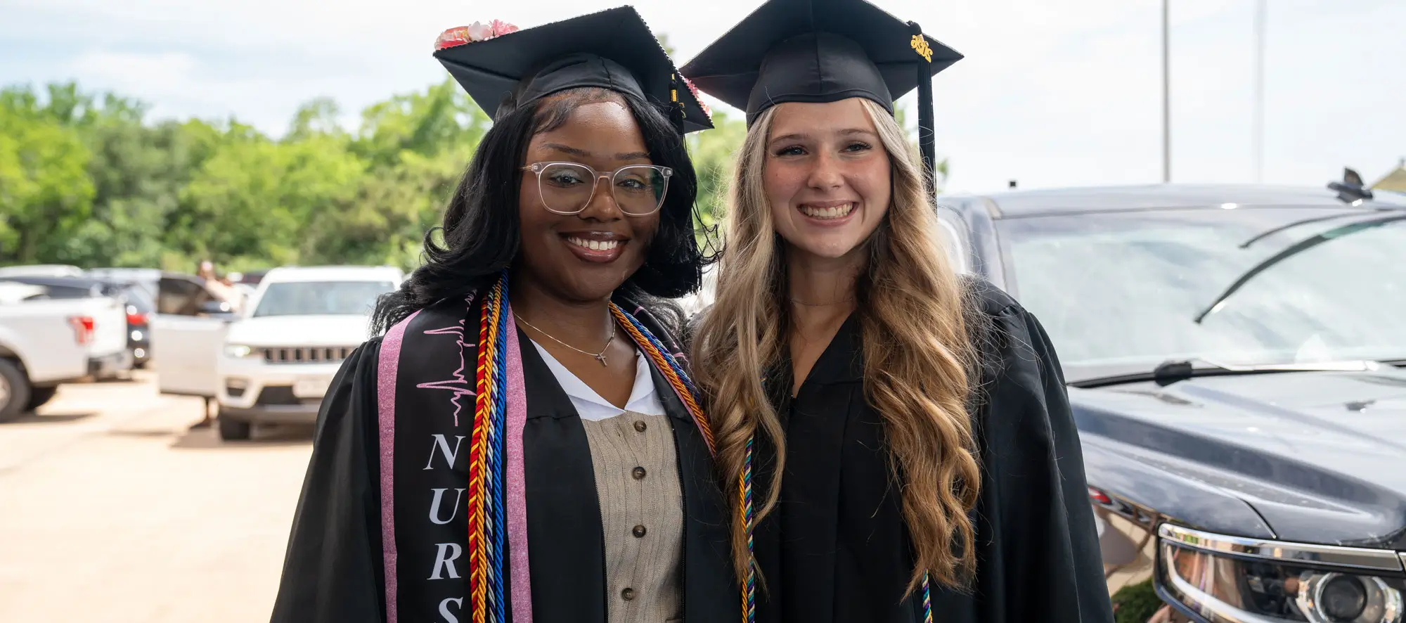 Two female graduates outside at commencement ceremony