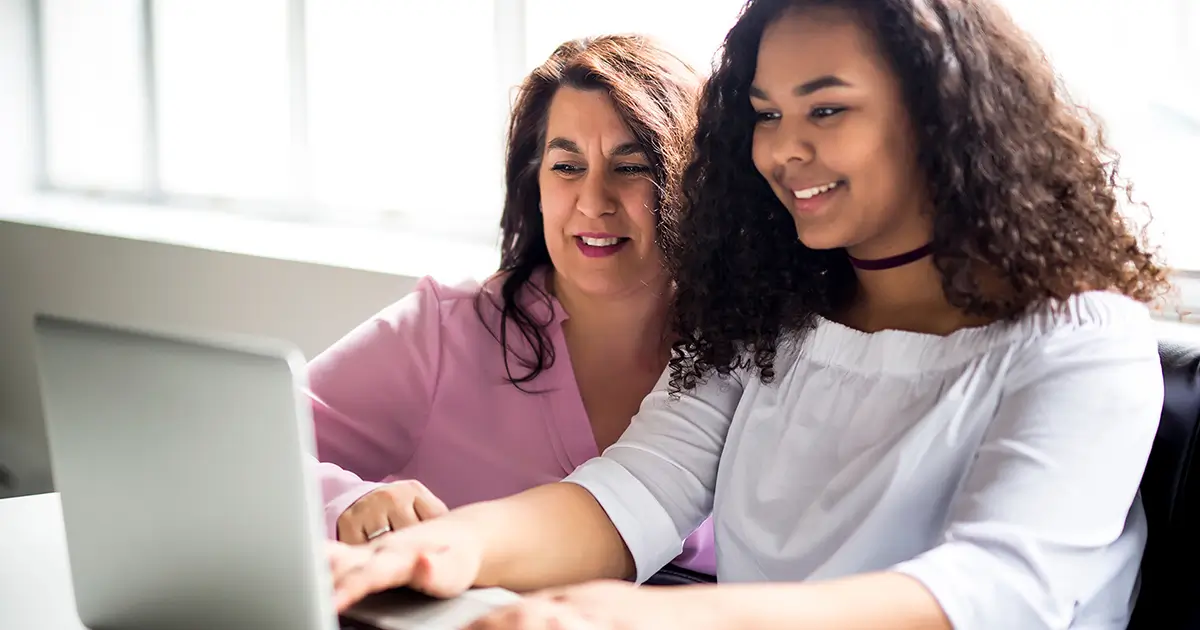 Mother and daughter looking at a laptop together.
