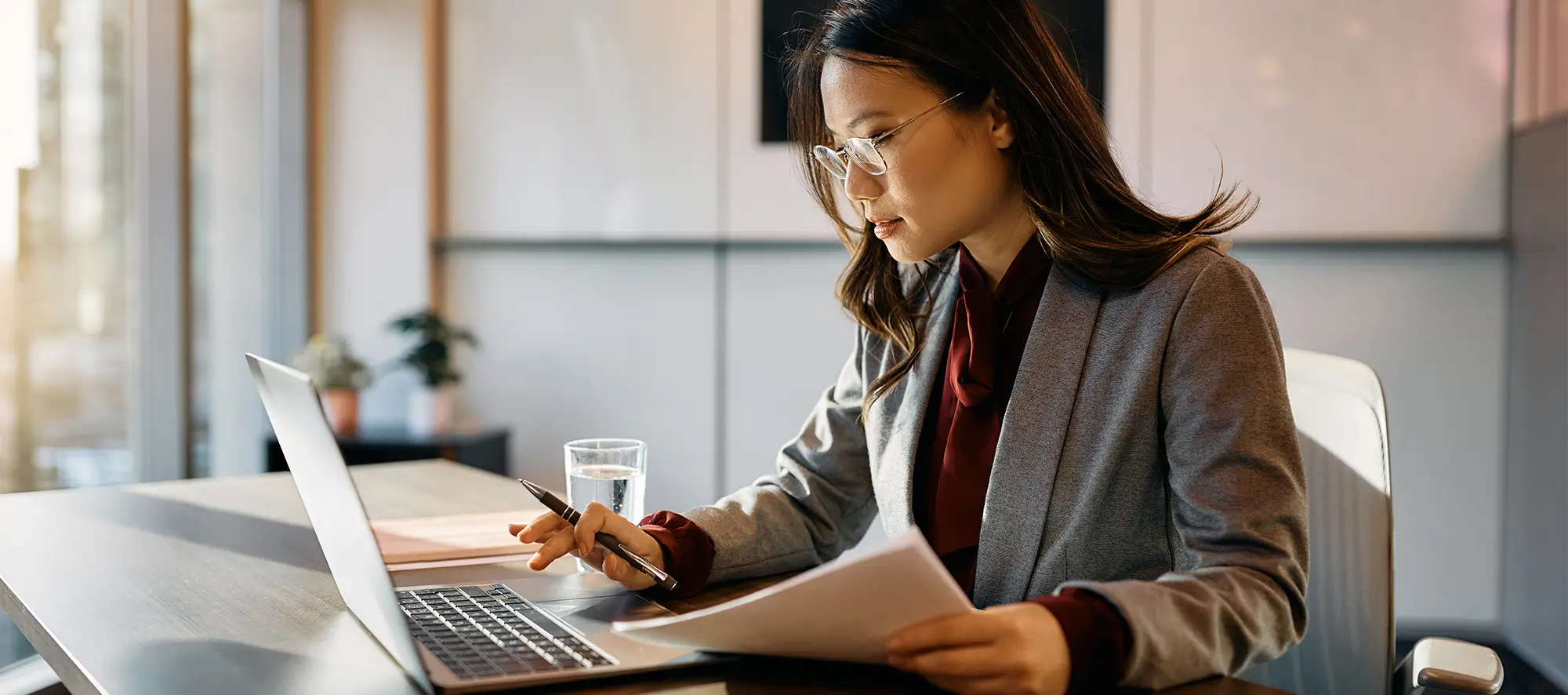 woman at desk with computer and paperwork.