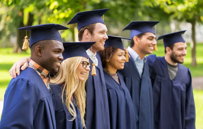 Graduation and people concept - group of happy international students in mortar boards and regalia outdoors