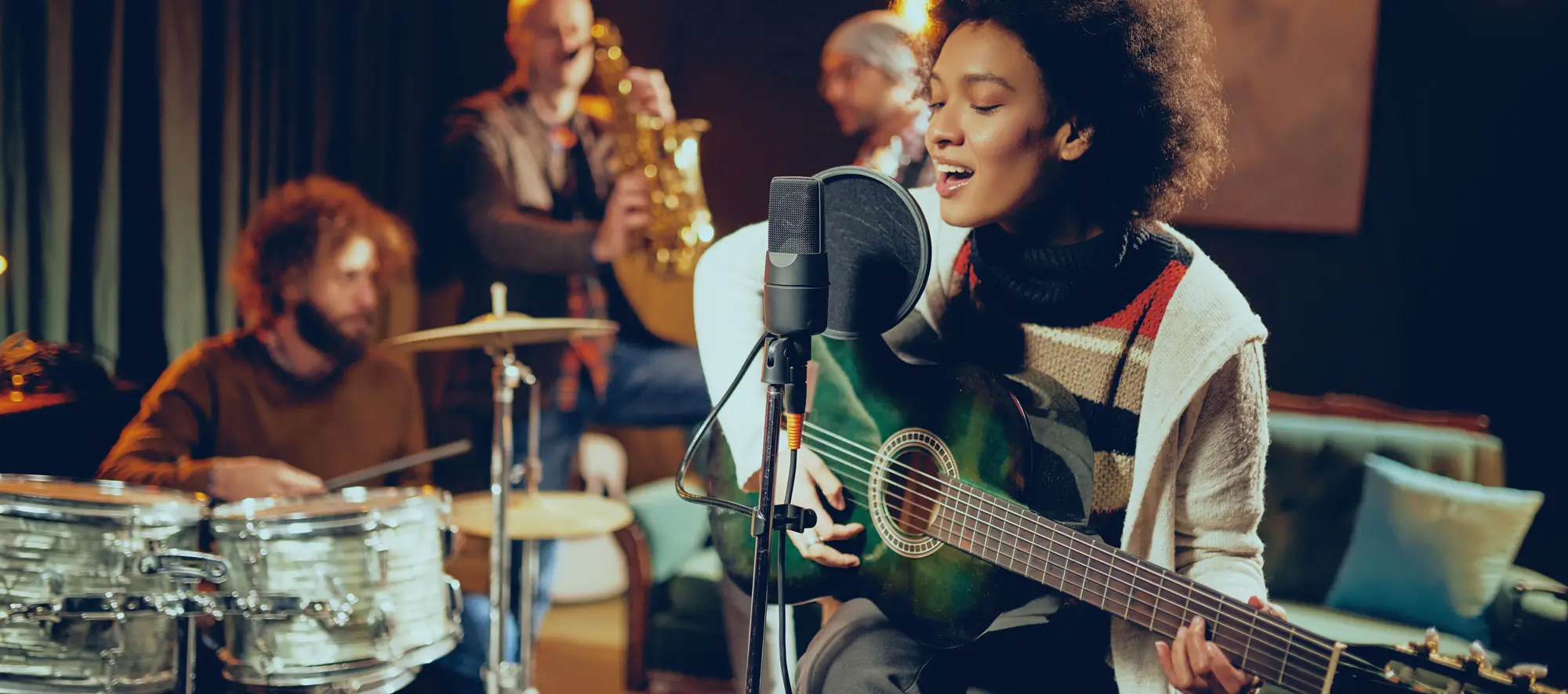 Young woman playing acoustic guitar on stage with band