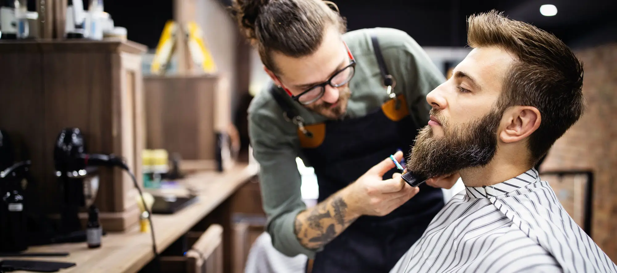 Happy young man visiting hairstylist in barber shop