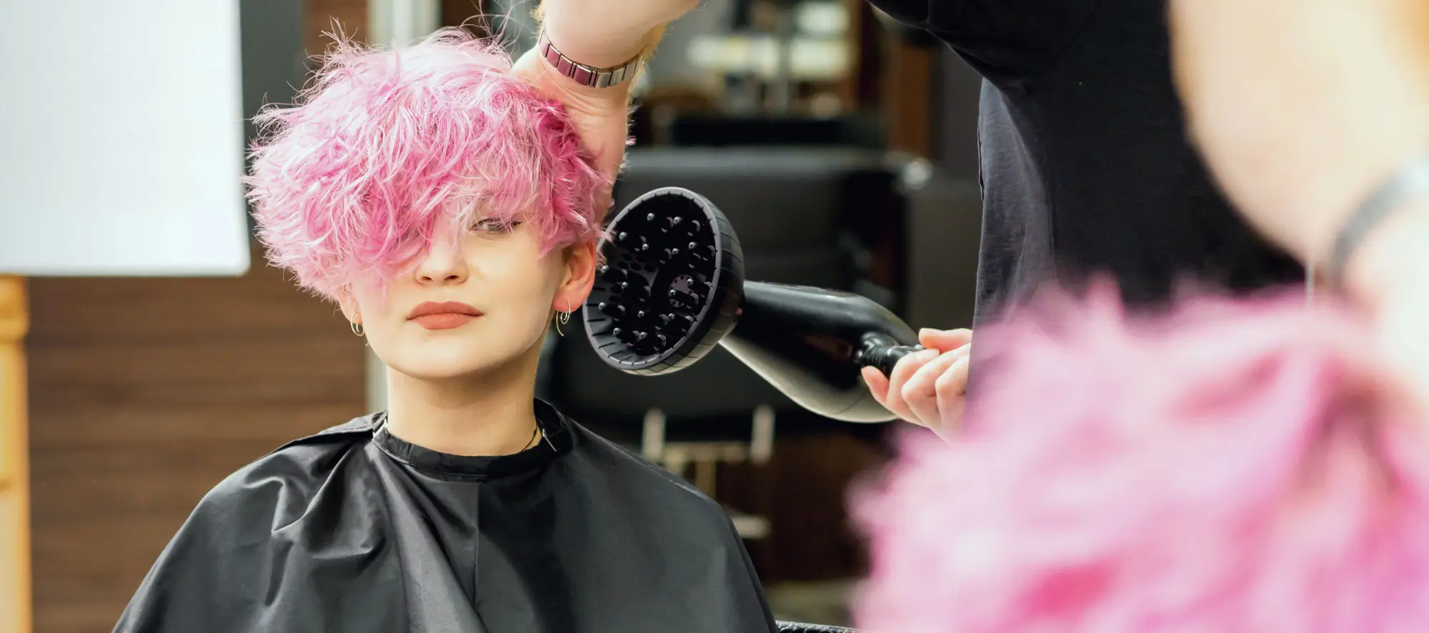Woman at salon with freshly dyed pink hair.