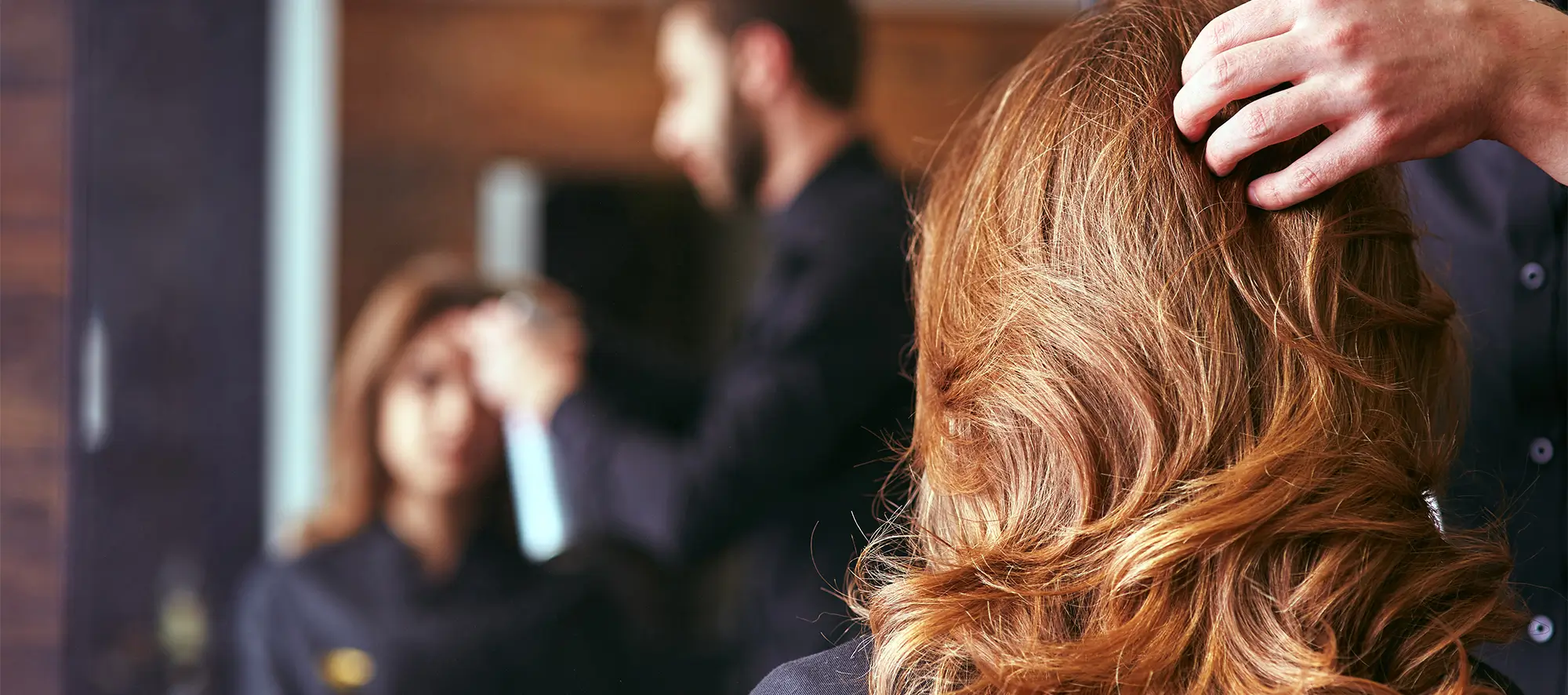 Hairdresser styling woman's hair in a salon.