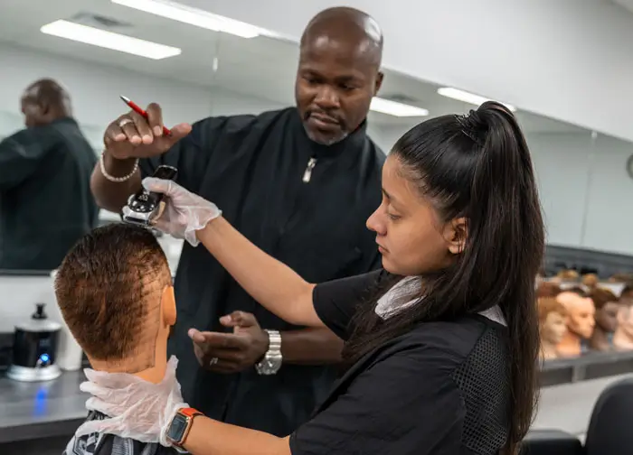 Barbering student getting help from instructor