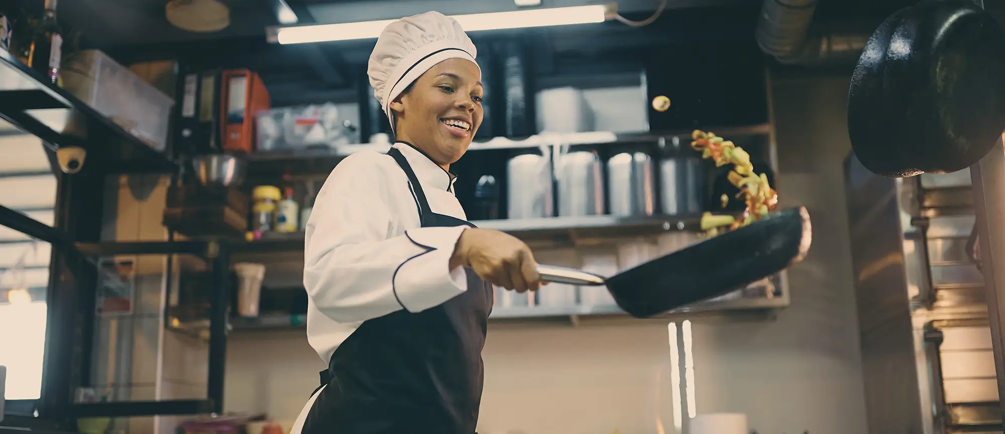 Chef in a kitchen flipping food in the air with a skillet
