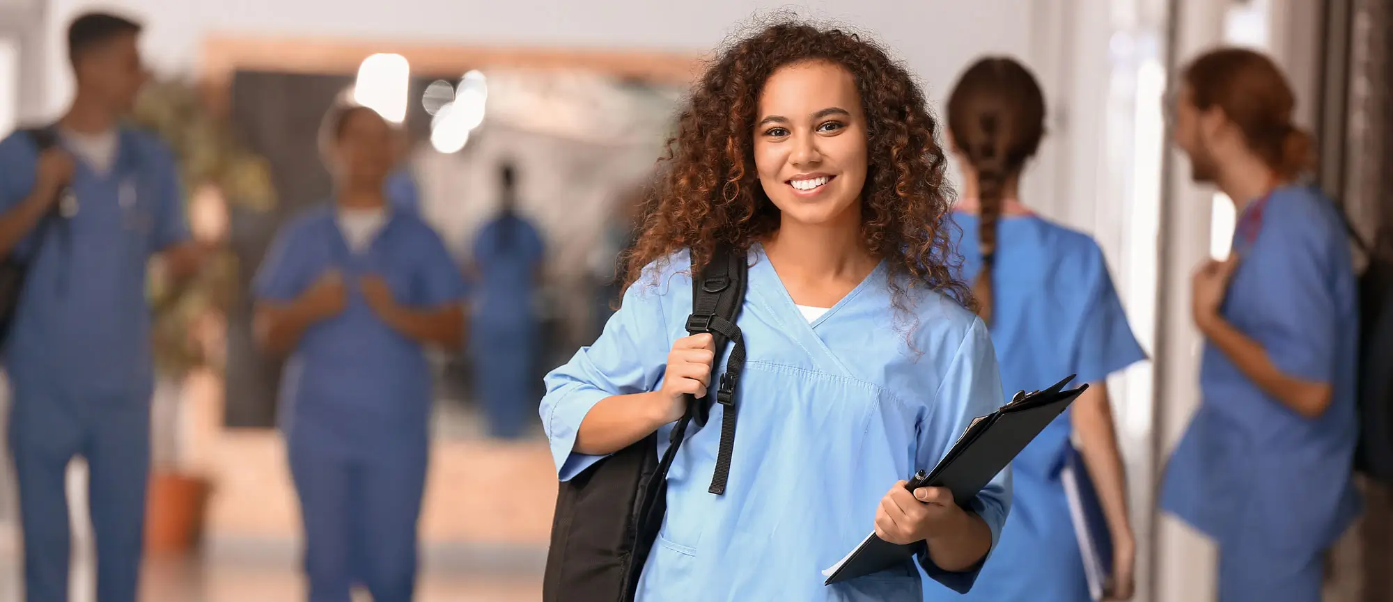 Female nurse in hallway with medical professionals in the background