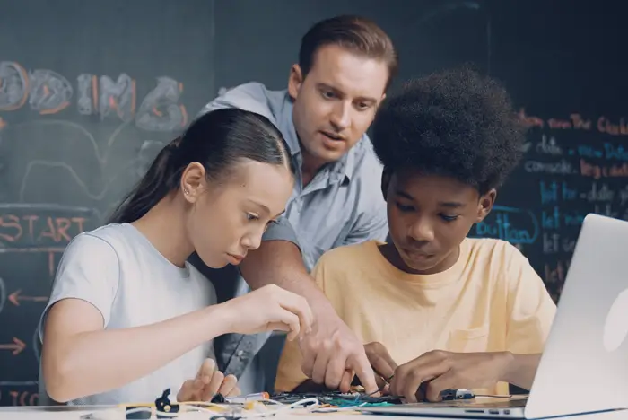 Teacher helping young kids with a computer project
