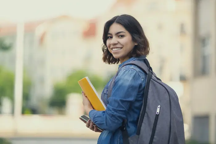 Female student with backpack and yellow notebook