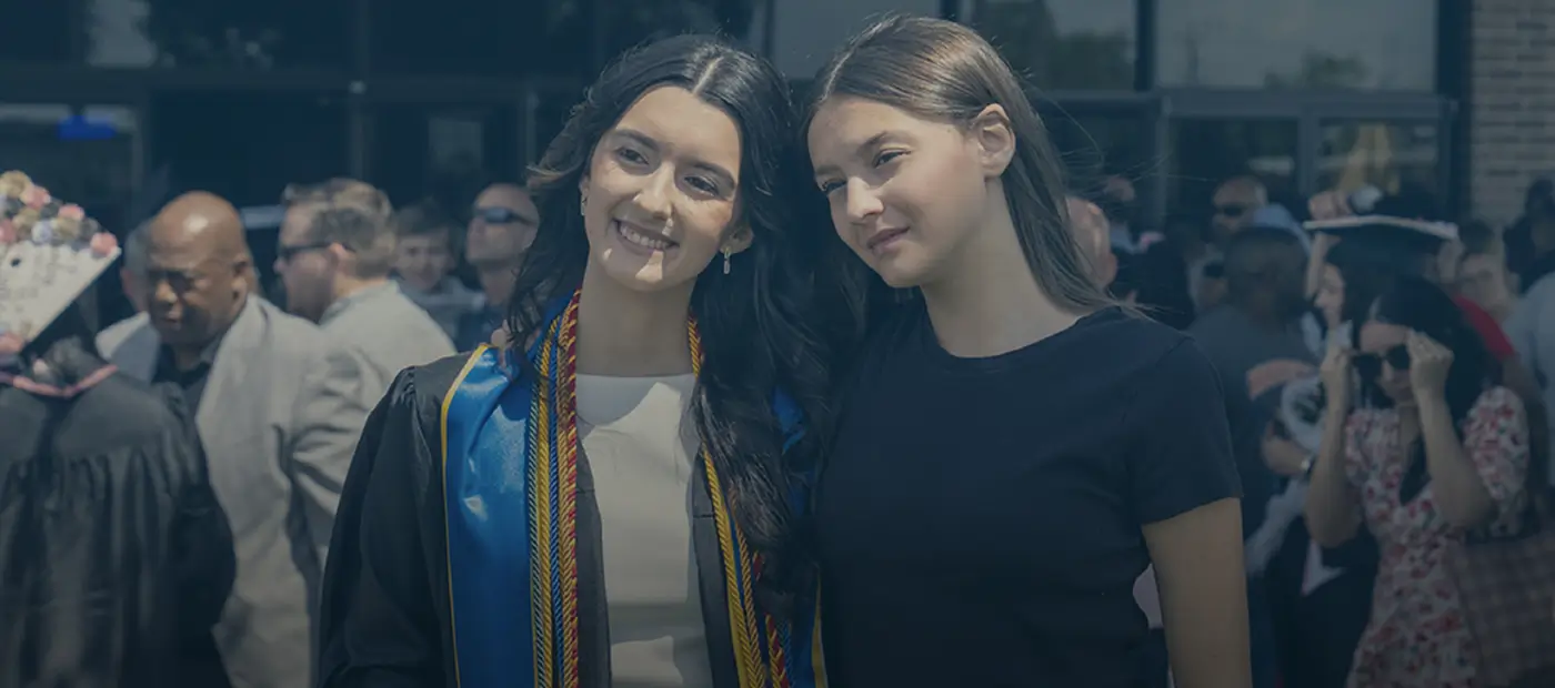 A graduate and her friend outside of graduation ceremony.