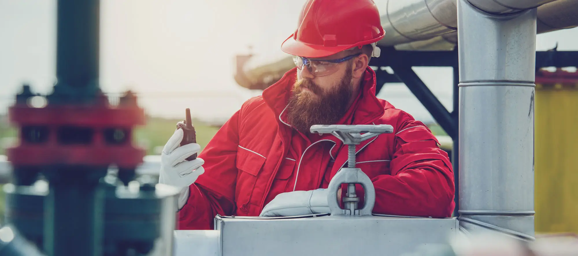 Engineer in hard-hat. Face behind pipeline machinery, fuel and oil refinery.