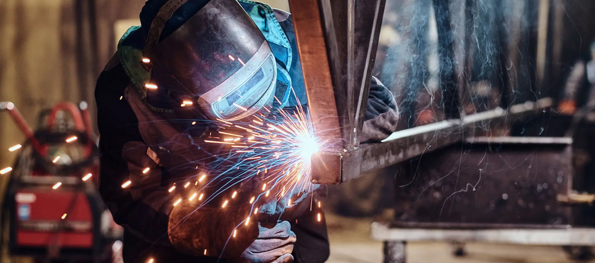 Welder in class welding a pipe with sparks flying