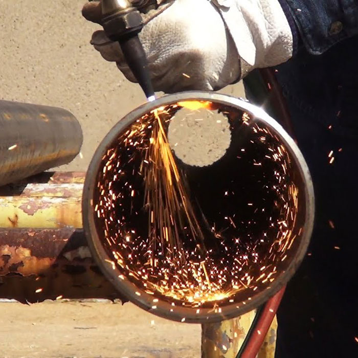 Welder cutting a pipe outside
