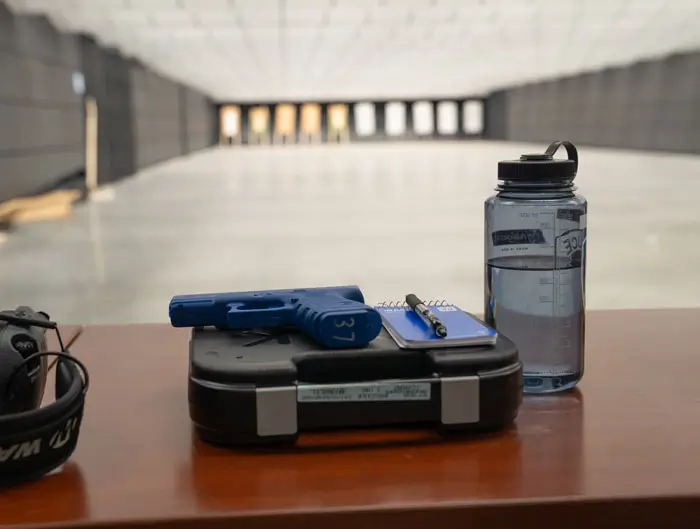 Closeup of gun and safety equipment inside firing range with targets in the distance