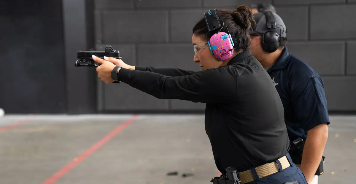 Instructor next to woman shooting a pistol.
