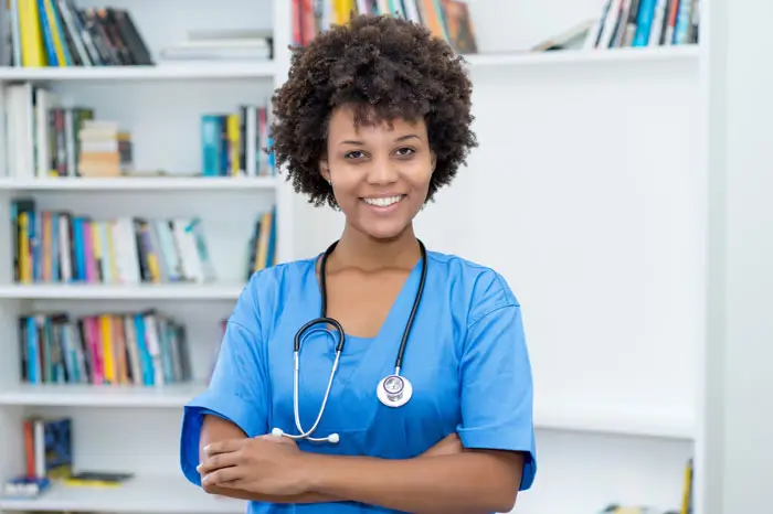 Nursing Aide standing with arms crossed and smiling at the camera.