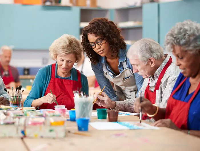 Group of older adults in an art class with their instructor overlooking.
