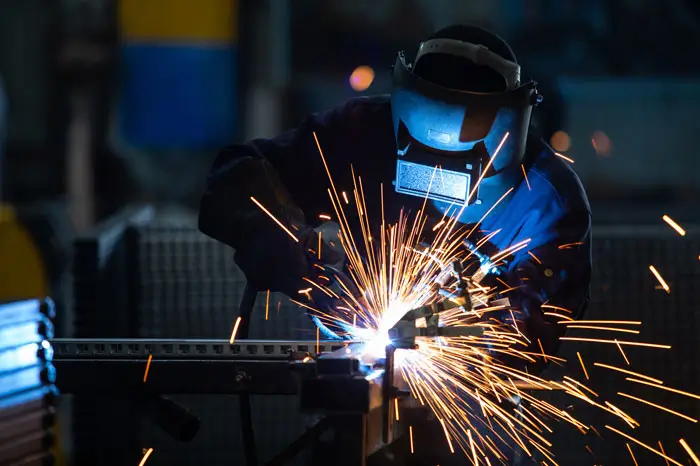 Welder welding in full equipment with flying sparks.