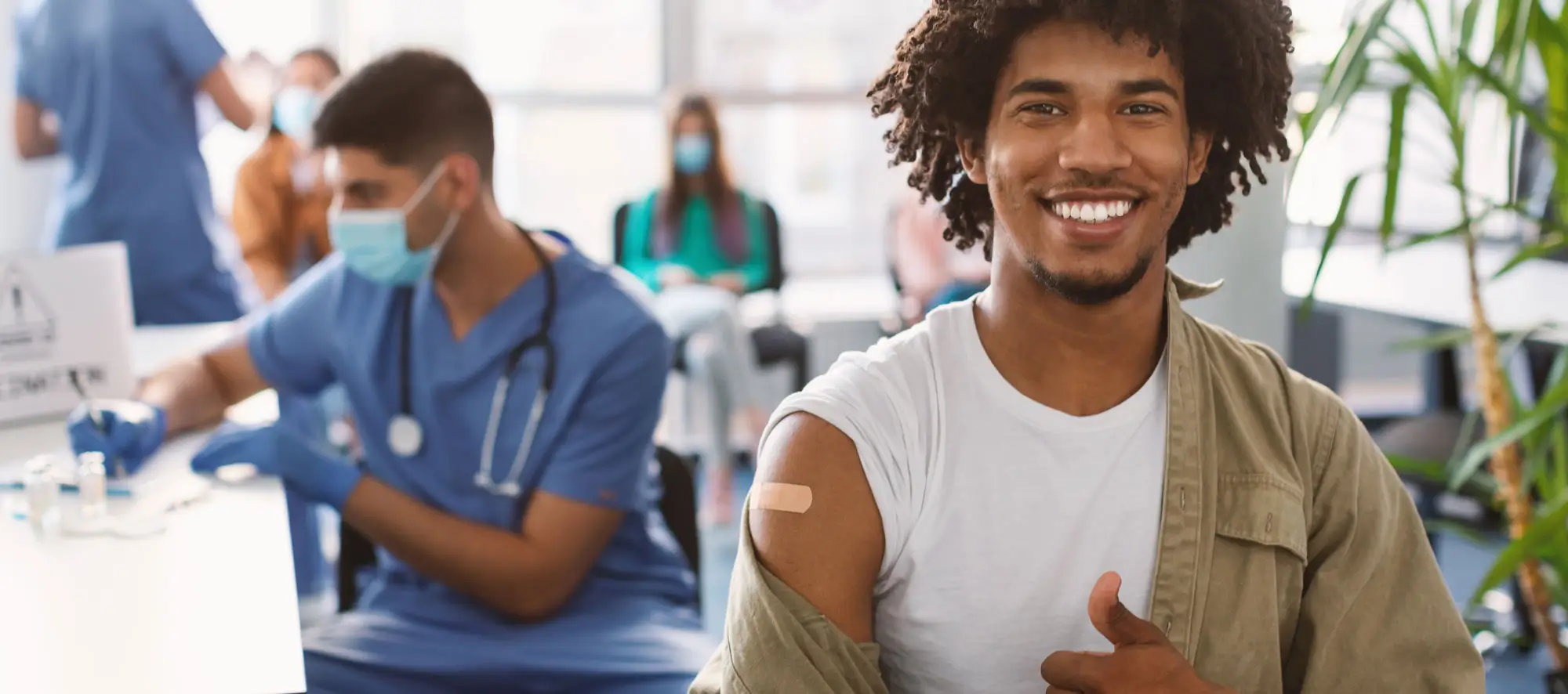 Vaccinated Black Man Gesturing Thumb Up And Showing Arm With Adhesive Bandage After Vaccine Injection.