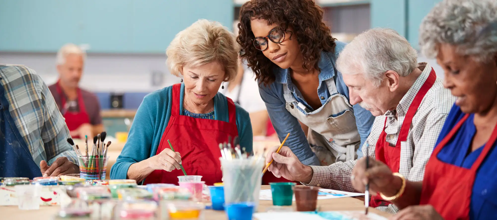 Group of older adults in an art class with their instructor overlooking.