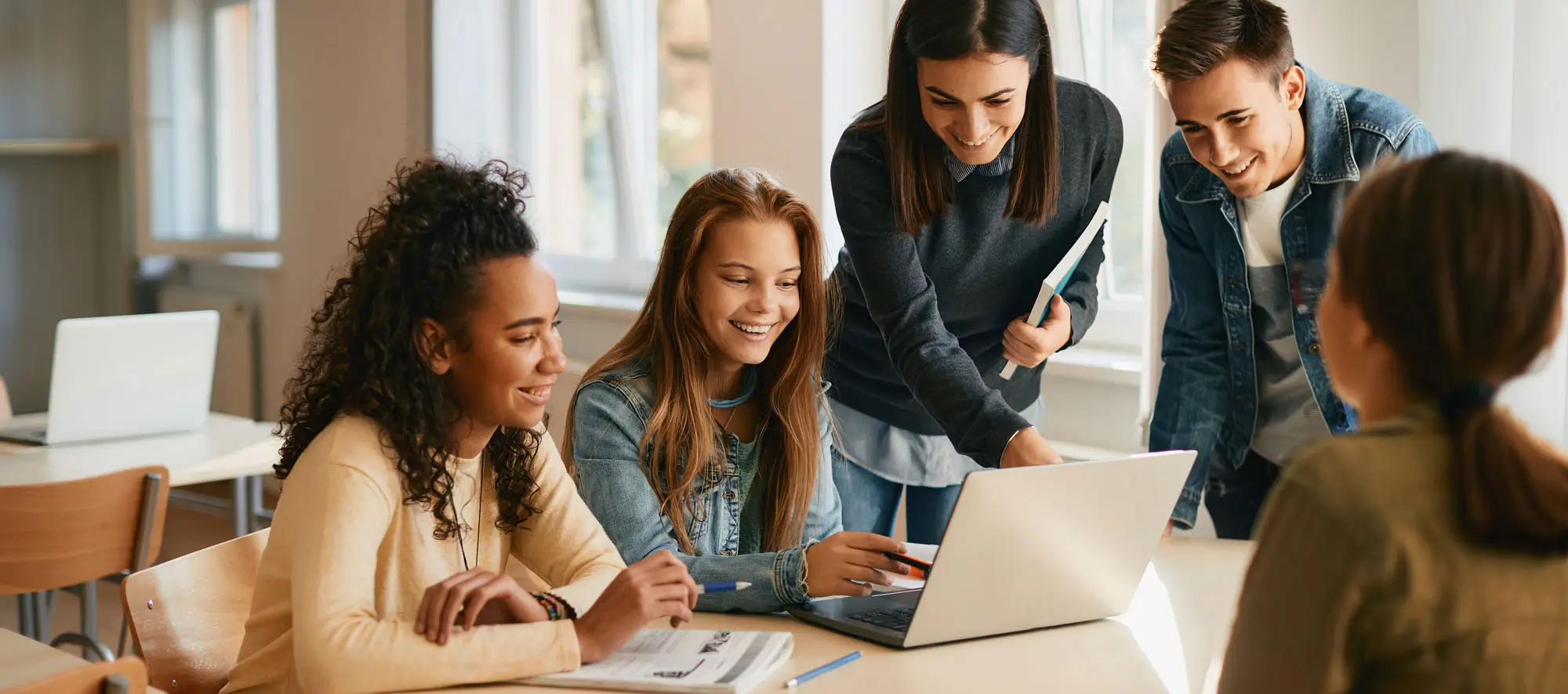 Happy students use laptop with their advisor.