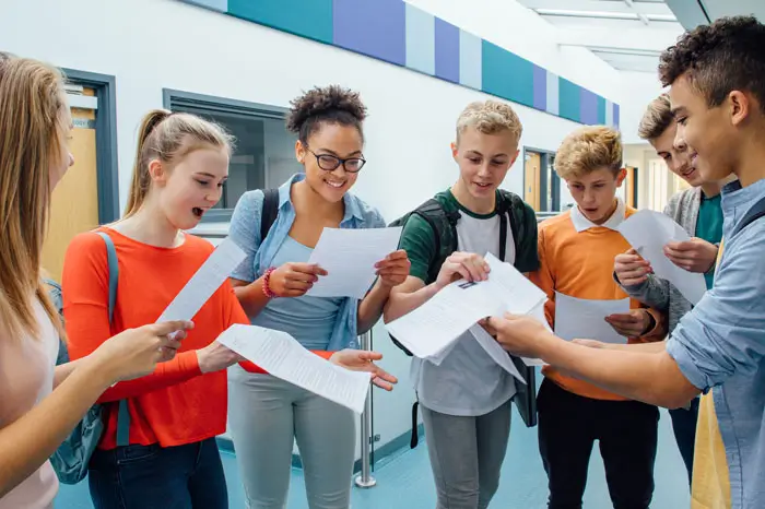 High school students in hallway passing out graded papers