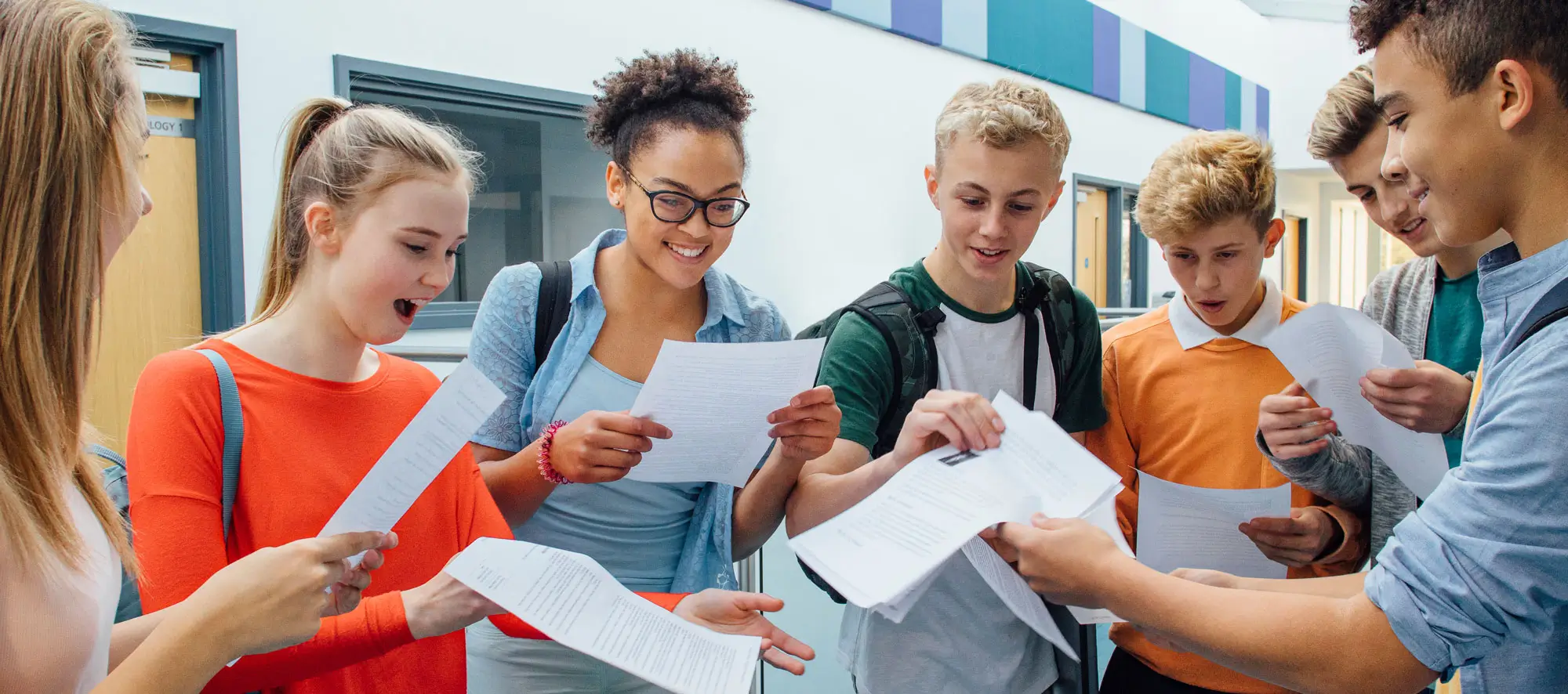 High school students in hallway passing out graded papers.