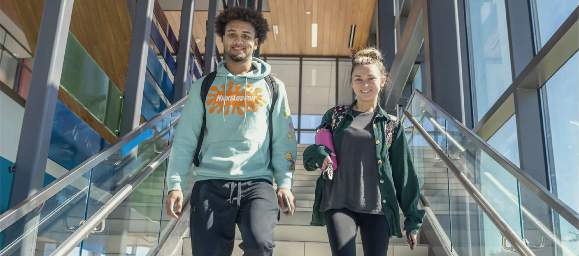 Two young students walking down colorful stairwell.