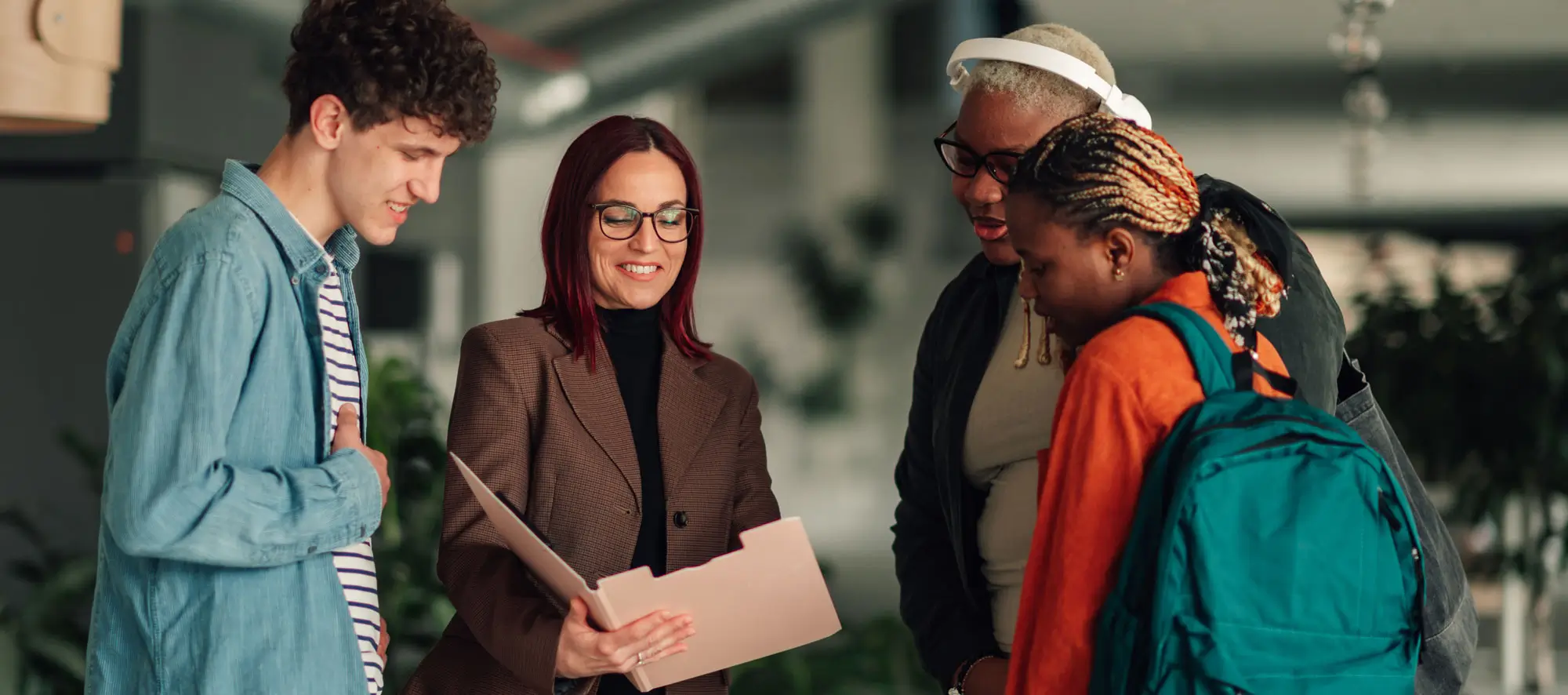 Group of students standing around an advisor, showing them information inside a folder