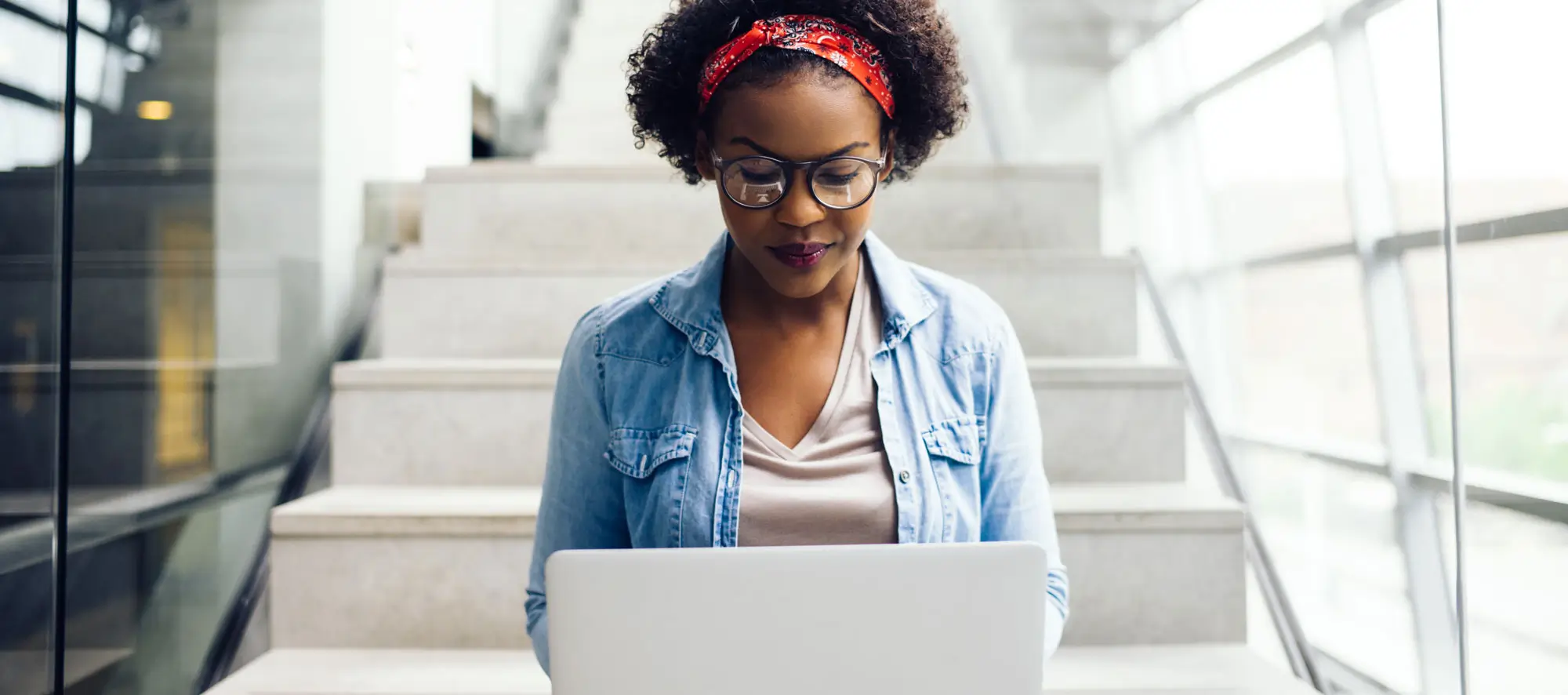 Focused young student sitting on stairs using a laptop