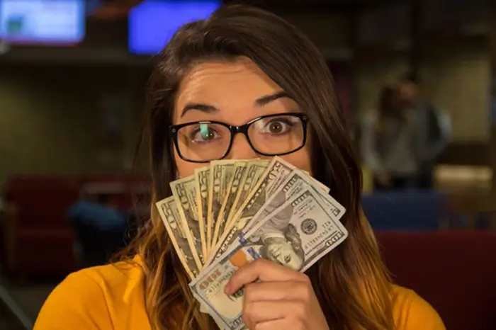 Female student with cash fanned out in front of her face.