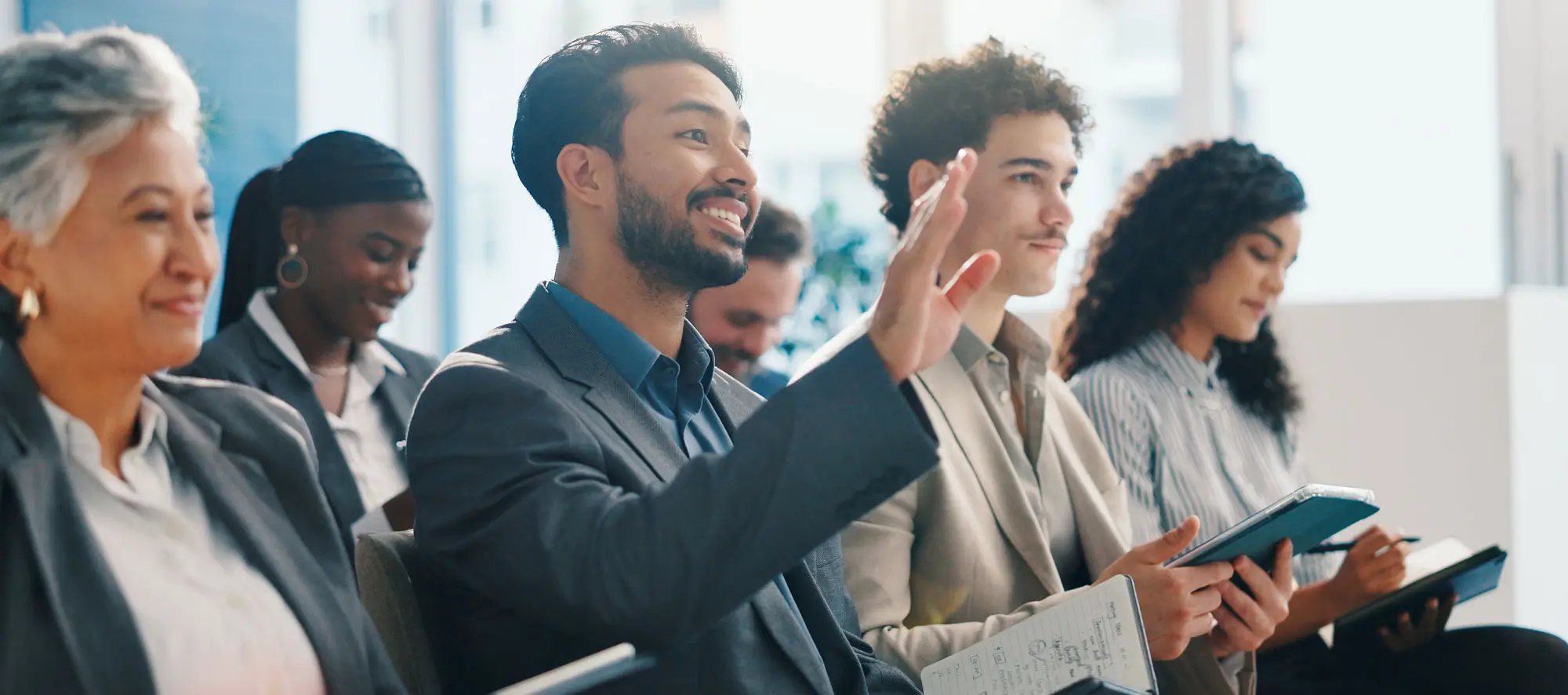 Group of people in a conference with a man raising his hand