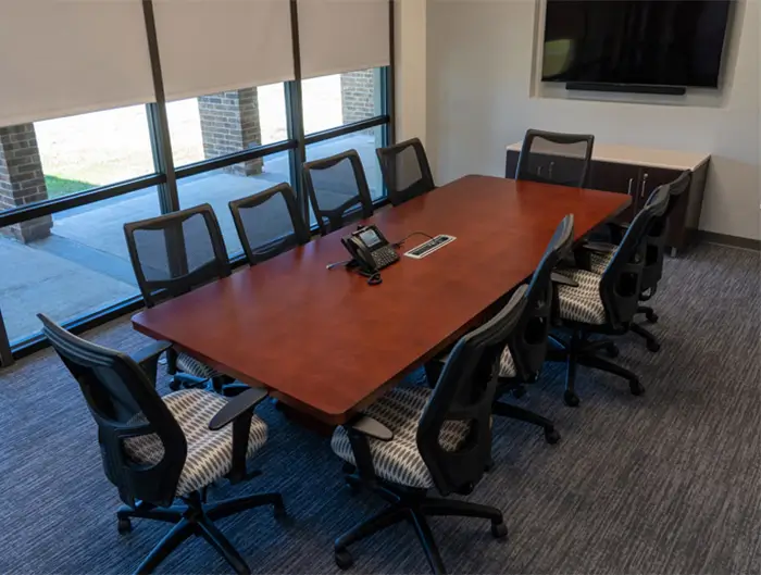 Small conference room table with 10 empty chairs.