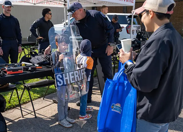 Little boy behind sheriff shield  at the Sheriff's both at College of the Mainland's Flock the Block event.