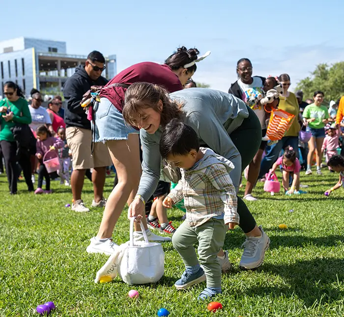 Young boy and family member participating in s easter egg hunt.