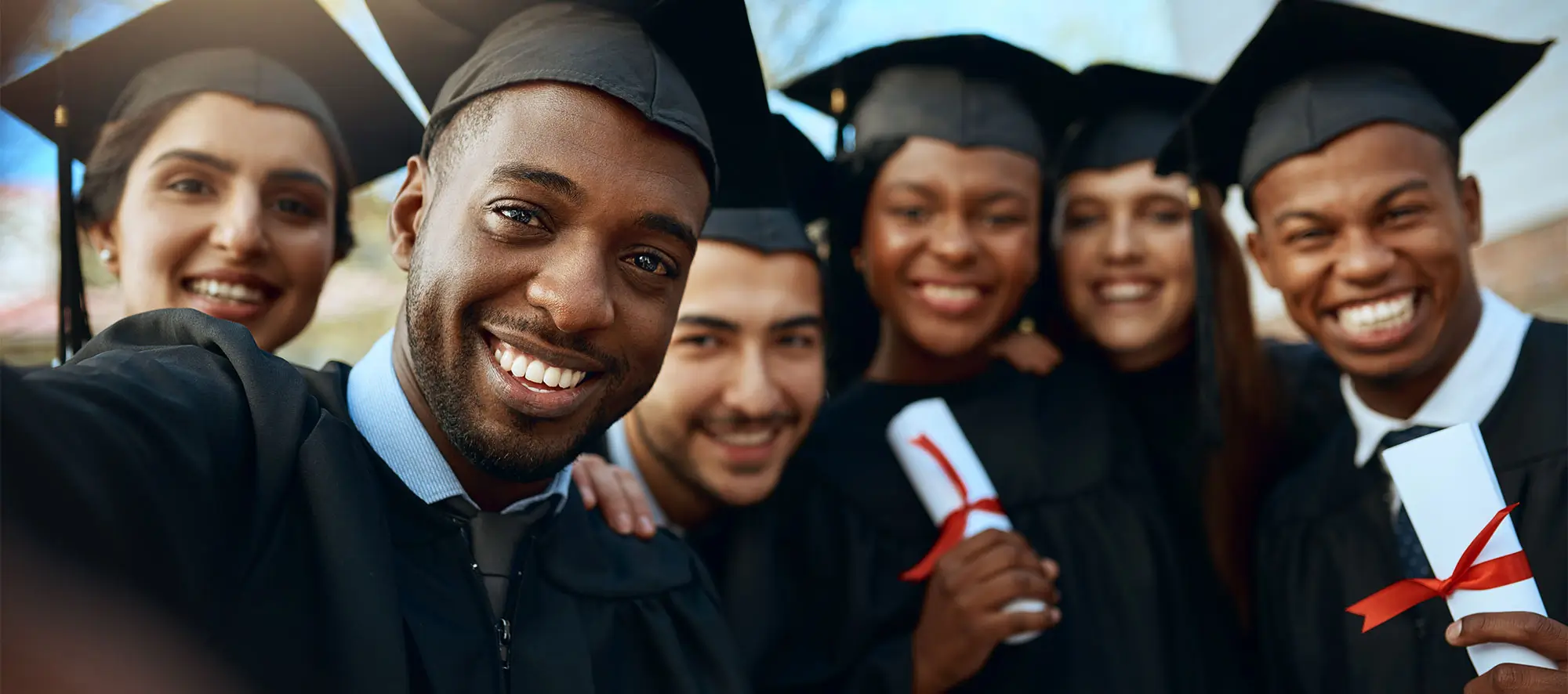Portrait of a group of students taking selfies on graduation day.