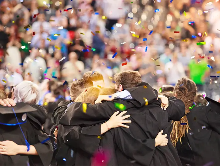 Students hugging each other as they graduate. 