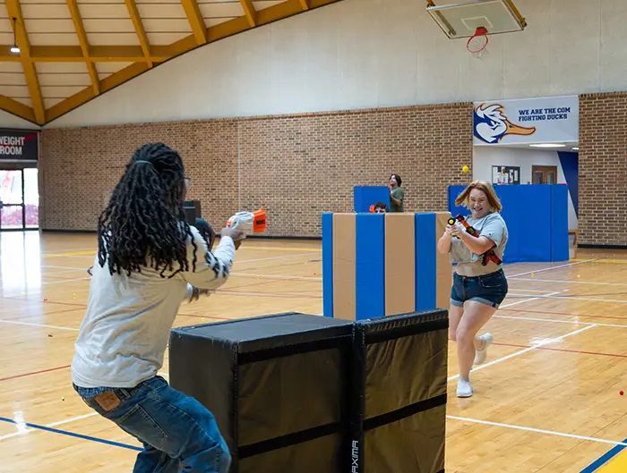 Students in COM gym playing with nerf guns. 