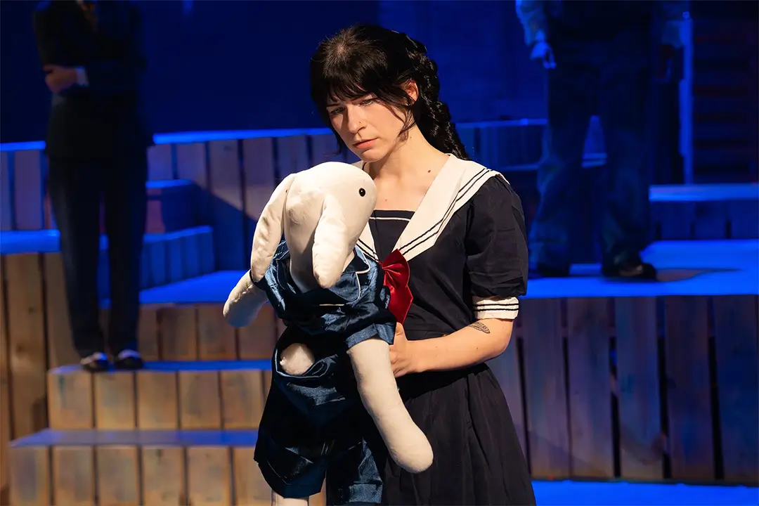 COM Theatre student Reagan Beam, portraying Woman One in The Miraculous Journey of Edward Tulane, holds Edward during a scene from the production.