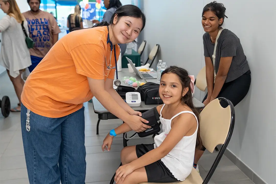Young community member receives blood pressure reading by local health organization.