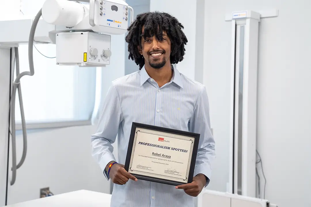 Robel Araya stands with his professionalism award in the College of the Mainland radiologic technology classroom.
