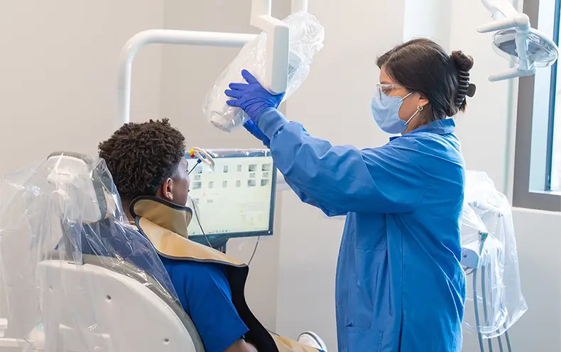 COM dental hygiene student Gabrielle Garza performs an x-ray on a patient.