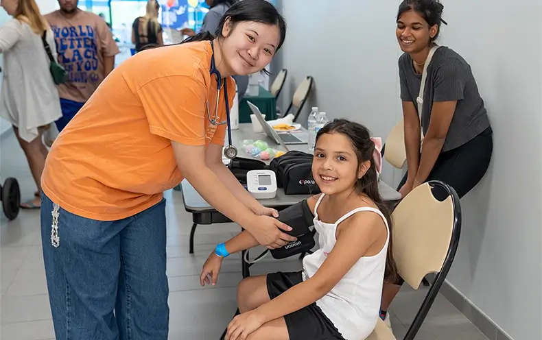 Young community member receives blood pressure reading by local health organization.