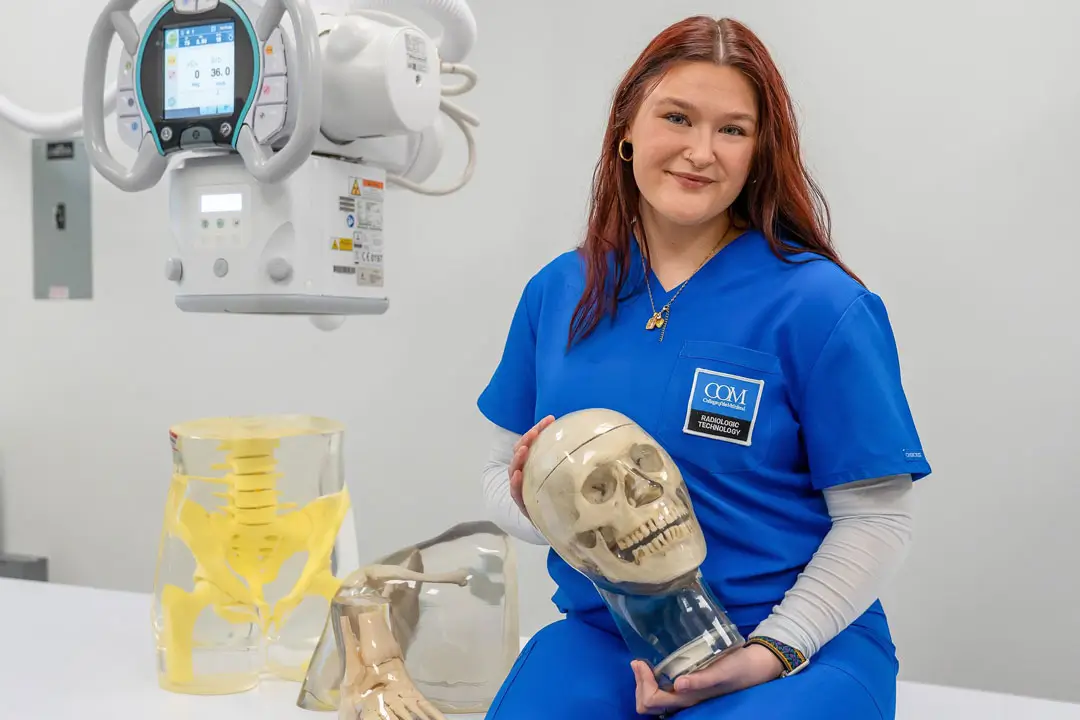Amanda Respondek in the COM Rad Tech lab holding an x-ray skull model.
